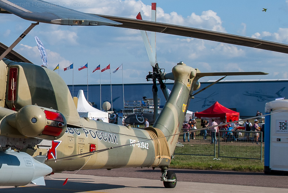 The Mi-28 has a scissor type, four blade tail rotor like the Apache, but it is on the left side of the vertical stabiliser and large, with a horizontal stabiliser on the opposite side. Image