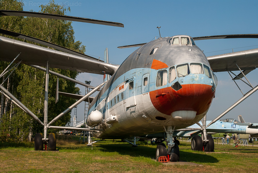 This close-up front view shows the two cockpits of the Mil V-12, airplane like fuselage, as well as the many struts that brace the wings and rotor/engine system. Image