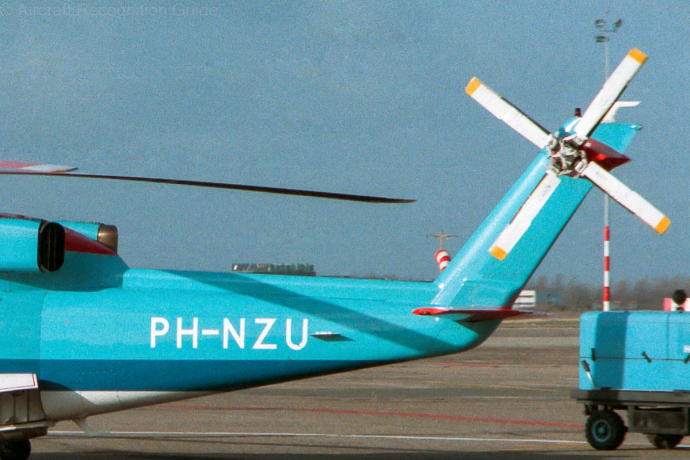 Starting with the S-76B, the rear looks different with a taller, narrower vertical stabiliser, and a shorter tail cone. Also note the different heart of the tail rotor. Image